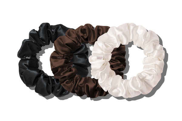 Three slip silk large hair scrunchies in black, chocolate, and white, arranged overlapping on a clean white background.