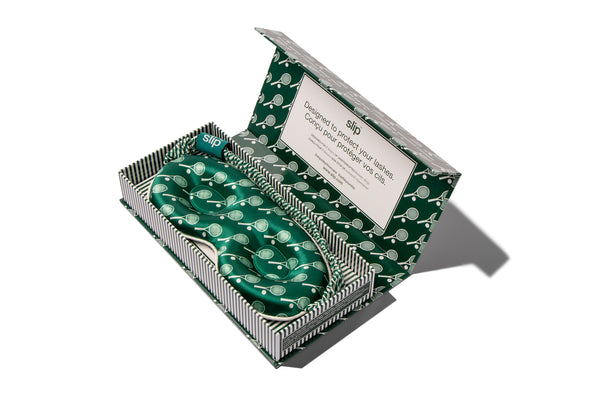 Green and white silk contour sleep mask in a box with a slip label on a white background