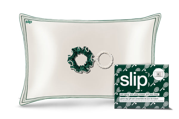 White silk pillowcase with green decorative trim/piping and slip branded packaging on a white background