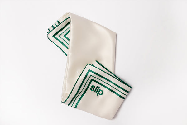 White silk pillowcase with green trim and slip logo embroidered.