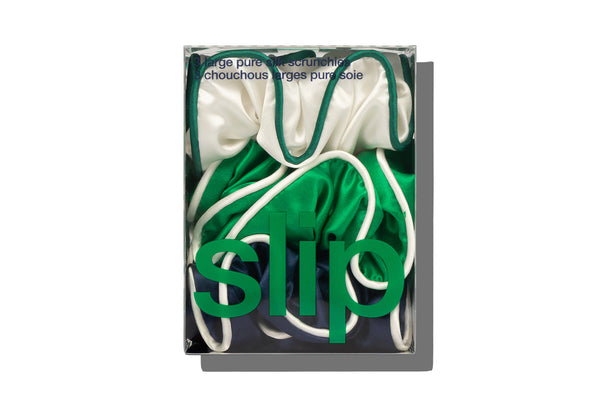 Green, navy and white large silk scrunchies in slip branded packaging on a white background