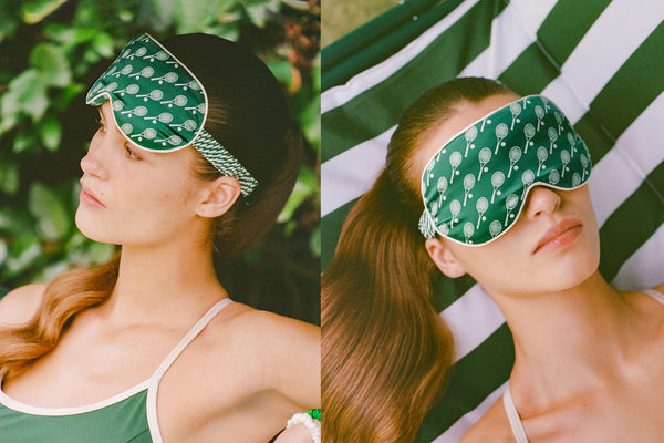 Woman wearing a green silk sleep mask with a tennis racket pattern, outdoors.
