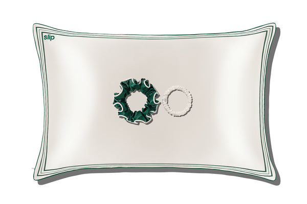 White silk pillow with green piping, green large silk scrunchie and white skinny scrunchies on a white background