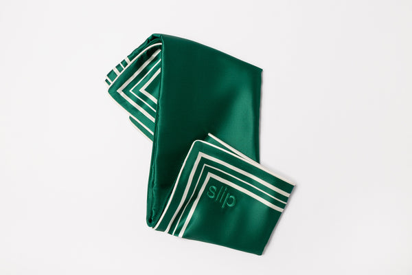 Green pure silk pillowcase with white piping and slip logo embroidered on a light grey background