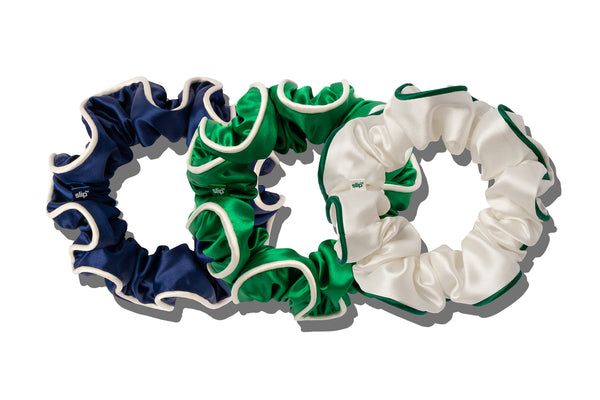 Three large silk scrunchies in navy, green, and white with contrast piping on a white background